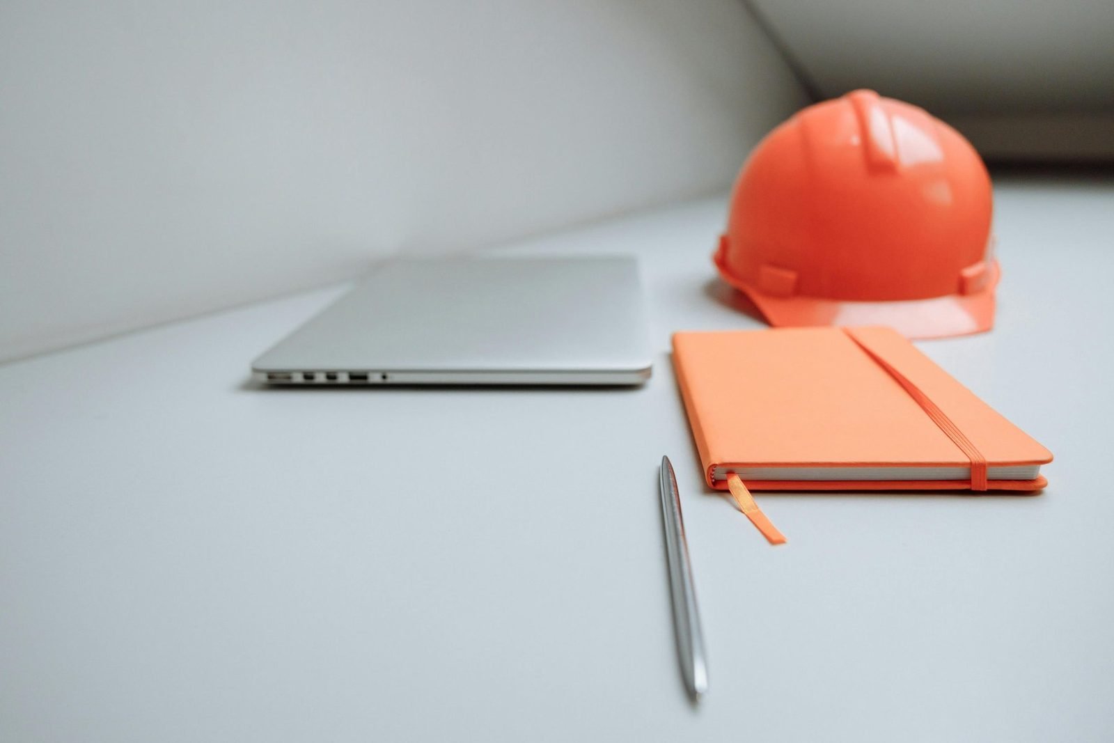 Notebook, caderno de anotações e capacete sobre mesa de trabalho técnico