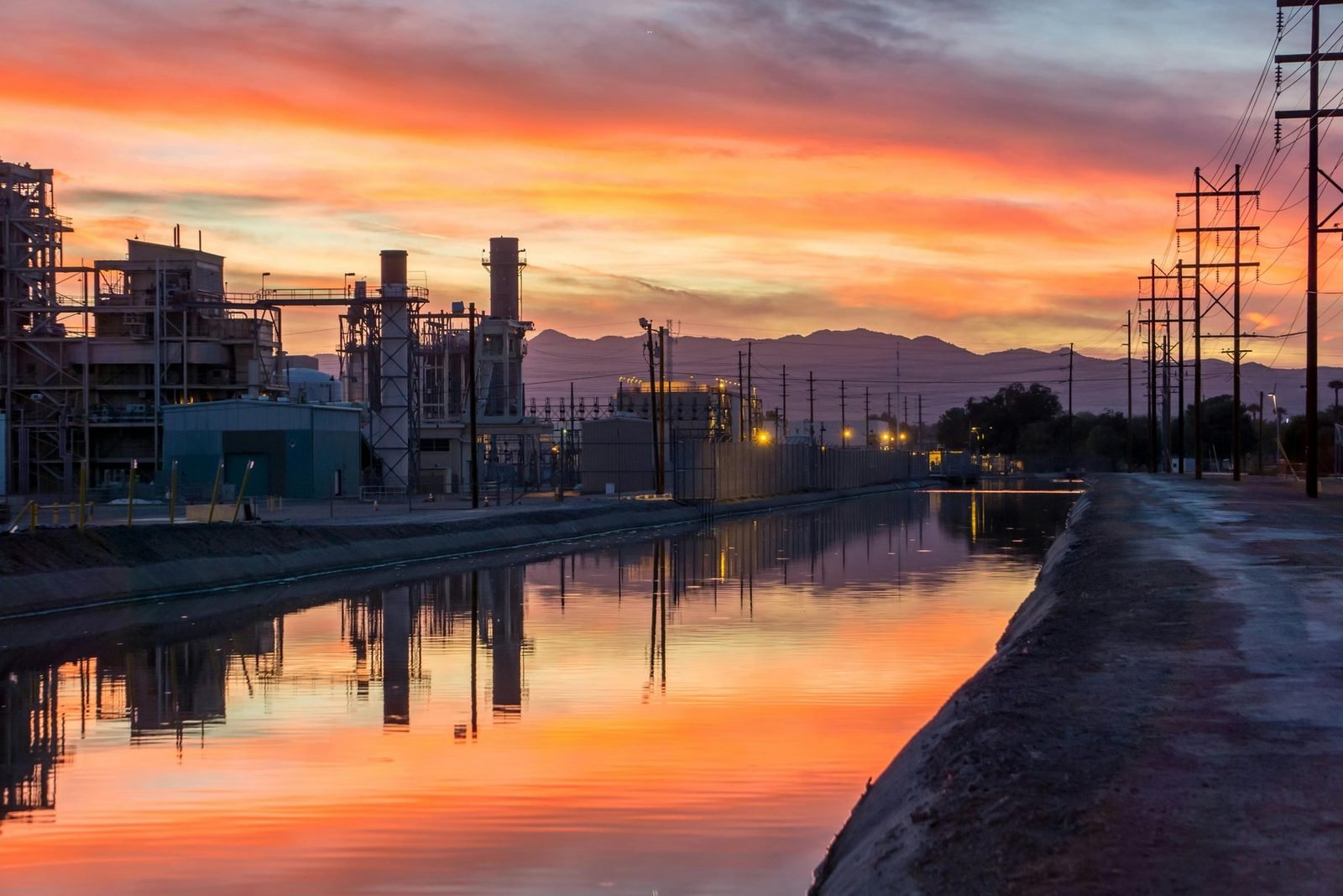 Planta industrial ao pôr do sol refletida em canal