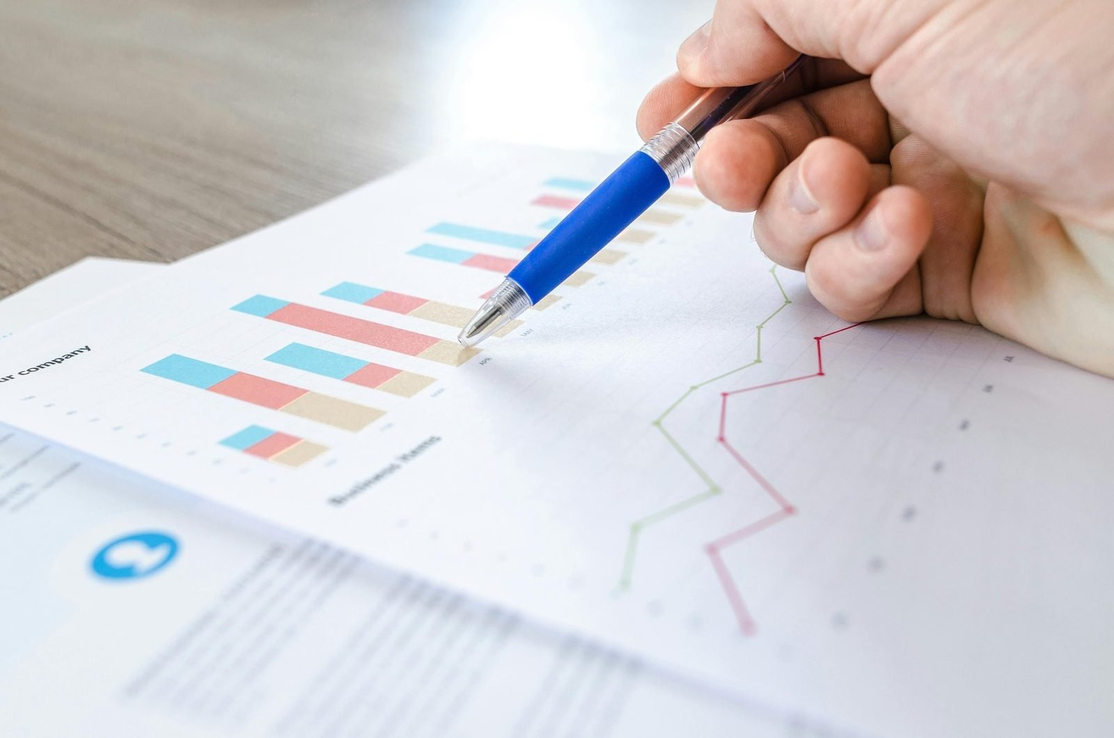 Mão com caneta analisando gráficos de resultados