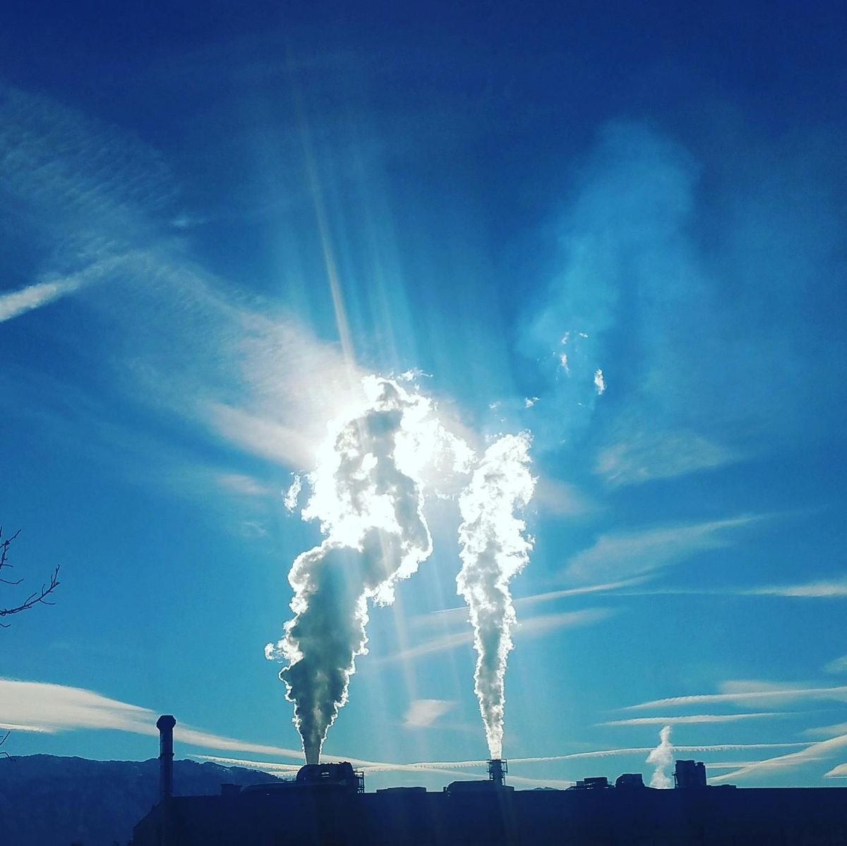 Plumas de vapor saindo de chaminés industriais contra o céu azul