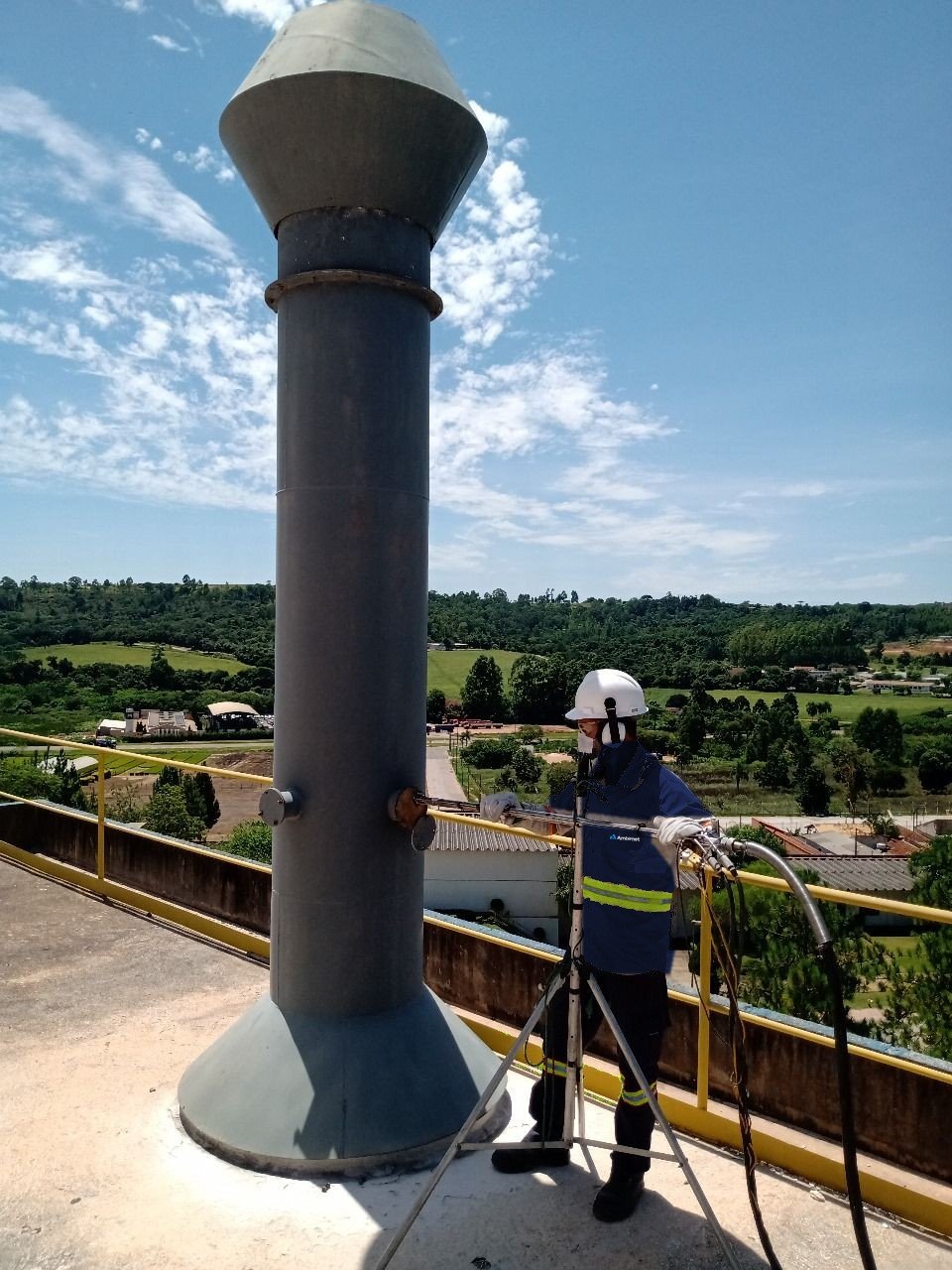 Técnico da Ambimet com o fardamento de campo durante amostragem de emissões no alto de uma chaminé industrial